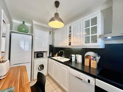 une cuisine avec des armoires blanches et un comptoir noir dans l'établissement Savannah appartement proche Carlton, by Welcome to Cannes, à Cannes