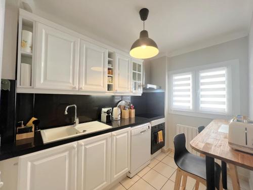 - une cuisine avec des placards blancs, un évier et une table dans l'établissement Savannah appartement proche Carlton, by Welcome to Cannes, à Cannes