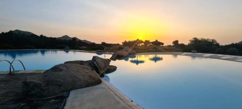 una gran piscina de agua con una puesta de sol en el fondo en villa 32, en Castiadas