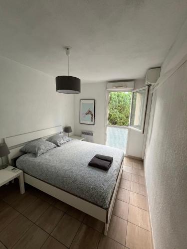 een witte slaapkamer met een bed en een raam bij Charmant F2 Port Marianne (15 Min Plages/Centre-ville) in Montpellier