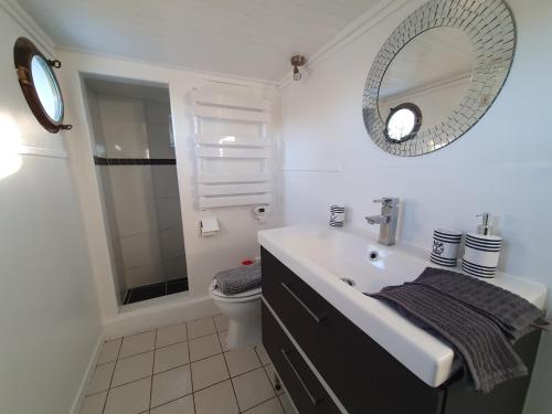 La salle de bains blanche est pourvue d'un lavabo et d'un miroir. dans l'établissement EXIGEHOME - La Perle Jaune du Port Marly - 25 min de Paris, à Le Port-Marly