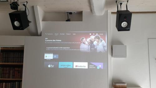 un écran de projection sur un mur avec deux haut-parleurs dans l'établissement BACKSTAGE STUDIO, à Maury