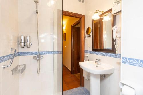 y baño con lavabo y ducha con espejo. en Escuder Apartamentos Turísticos, en Ribadeo