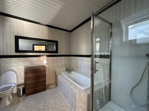 bagno con vasca, doccia e servizi igienici di Stylish big Jugend art nouveau apartment with balcony heart of Alesund ad Ålesund