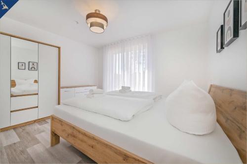 Habitación blanca con cama y espejo en An der Haffküste Haffkoje, en Zirchow