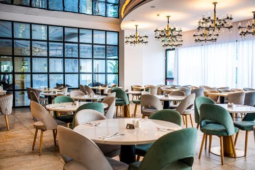 um restaurante com mesas, cadeiras e janelas em At Herbal Boutique Hotel & Spa em Protaras