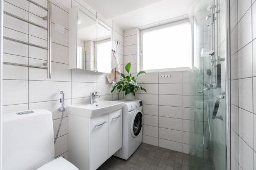 a white bathroom with a washing machine and a sink at Kodikas kahden makuuhuoneen asunto Tikkurilassa in Vantaa