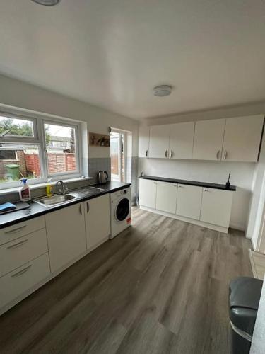 a large kitchen with white cabinets and a wooden floor at 30 min STN or to central London in Enfield Lock