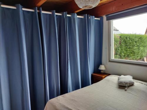 1 dormitorio con cortinas azules, 1 cama y ventana en Maison calme et lumineuse de plain-pied en Cabourg