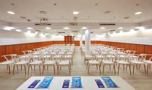 a room with rows of tables and white chairs at Hotel Samba in Lloret de Mar