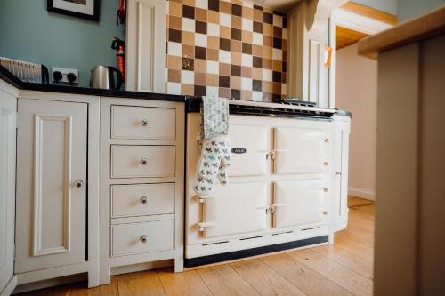 a kitchen with white cabinets and a checkered wall at Lower Bubbleton Penally in Penally