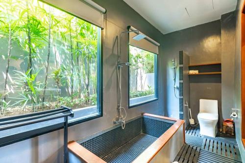 baño con ducha y aseo y ventana en Casa Asiatique — 5BR Villa in Laguna & Layan Beach, en Phuket