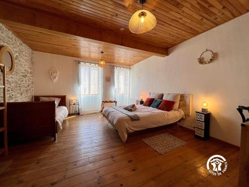 um quarto com uma cama grande num quarto com tectos em madeira em L’Oiseau Doré em Bram