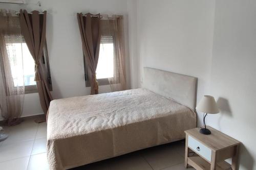 een slaapkamer met een bed en een tafel met een lamp bij Anesis with yard in Myrtos