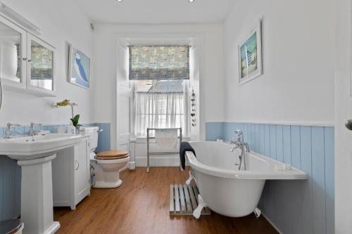 een badkamer met 2 wastafels, een bad en een toilet bij New Cross House St Davids in St. Davids