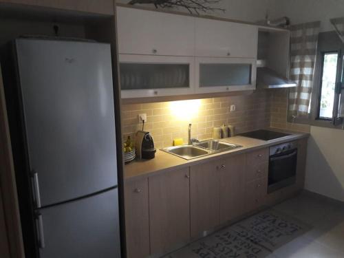 een keuken met een witte koelkast en een wastafel bij Anesis with yard in Myrtos