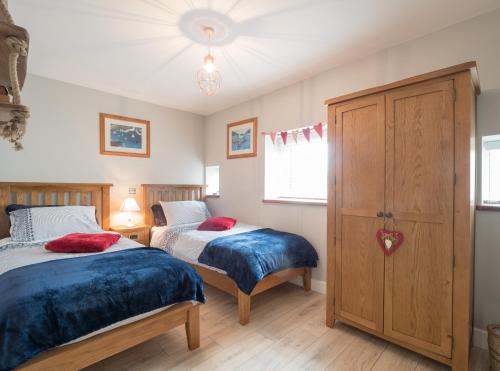 1 dormitorio con 2 camas y armario en White Fields Cottage Carmarthen, en Carmarthen