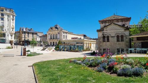 Un vieux bâtiment avec des fleurs dans un parc dans l'établissement Appartement F2 Le Puy-de-Dôme, à Châtel-Guyon