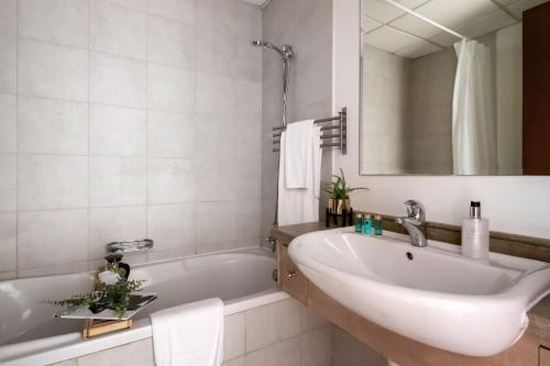 ein Badezimmer mit einem Waschbecken, einer Badewanne und einem Spiegel in der Unterkunft Frank Porter - Canal Residence in Dubai