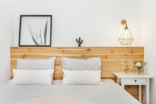 biała sypialnia z drewnianym zagłówkiem i białymi poduszkami w obiekcie Radziwiłłowska Old Town Apartments w Krakowie