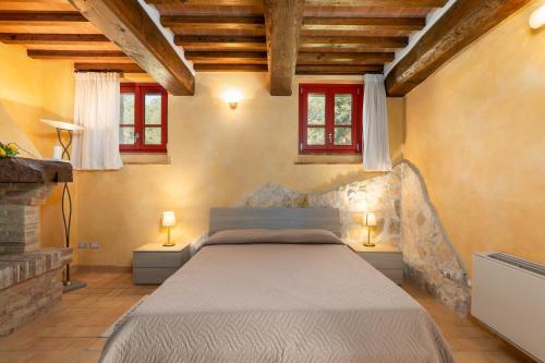 1 dormitorio con 1 cama y 2 ventanas en La Casina di Borgo Mommialla, en Gambassi Terme