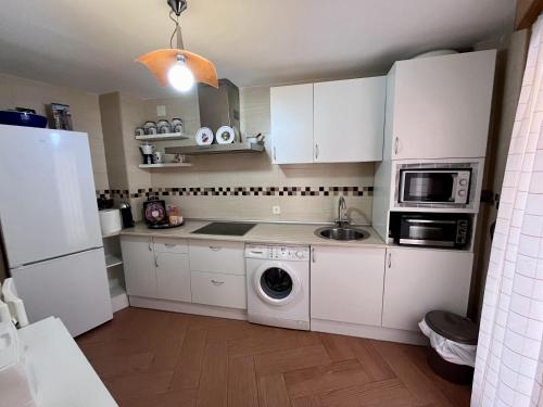 a kitchen with white cabinets and a washing machine at APARTAMENTOS TURISTICOS MONTASOL in Montánchez