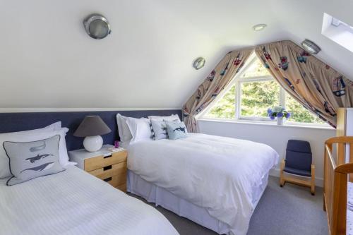 una camera da letto con due letti e una finestra di Cable Cottage a Salcombe