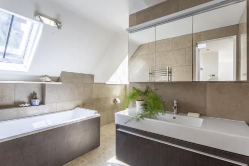 un bagno con vasca, lavandino e specchio di Cable Cottage a Salcombe