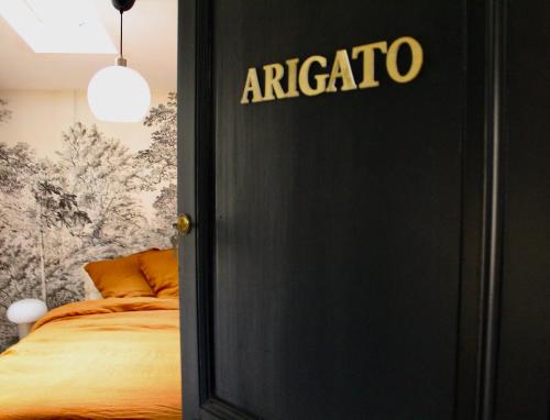 a black door with the word araccio on it next to a bed at Maison Merci - Maison d'hôtes in Carcassonne