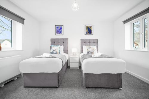 Duas camas num quarto branco com duas janelas em Stylish 2 Bedroom Apartment - Secure Parking - WIFI - Netflix - 27BC em Sleightholme