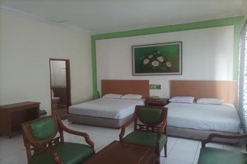 a hotel room with two beds and two chairs at Permata Hijau in Cirebon
