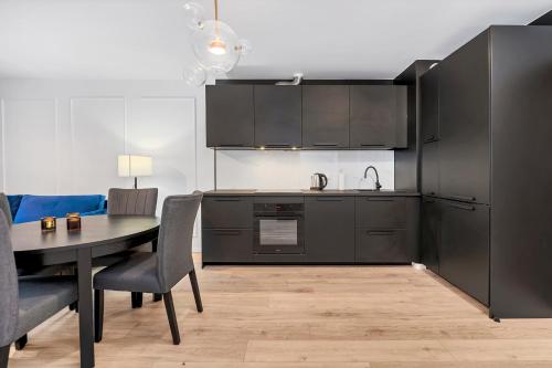 羅茲的住宿－Lumina 2-room apartment with beautiful view Lodz，厨房配有黑色橱柜和桌椅