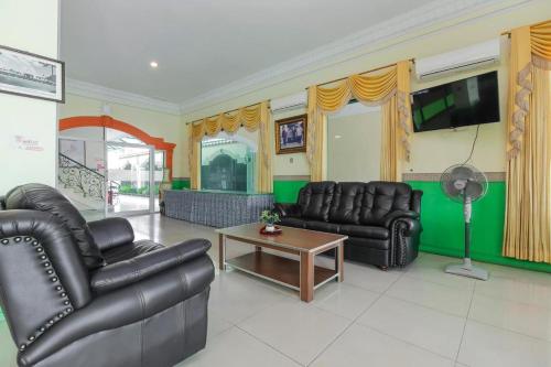 a living room with leather furniture and a flat screen tv at Permata Hijau in Cirebon