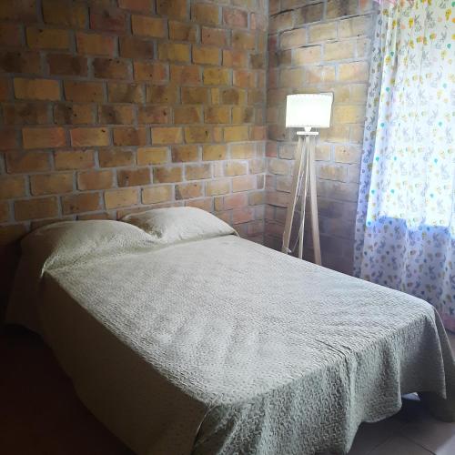 een slaapkamer met een bed en een bakstenen muur bij Casa 2 dormitorios in Oberá