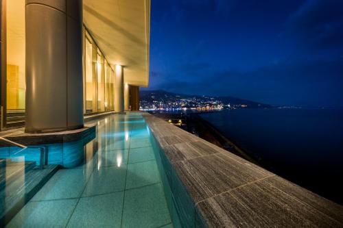 un edificio con vistas al agua por la noche en Atami Korakuen Hotel en Atami