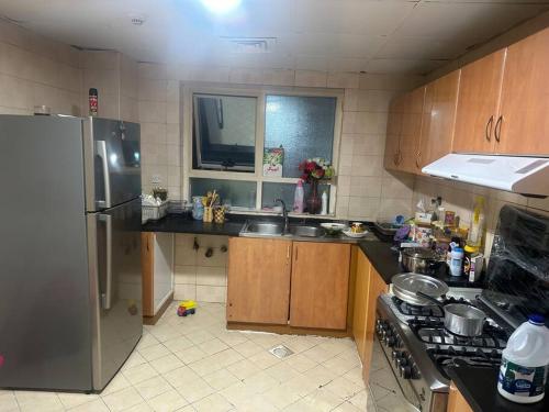 a kitchen with a stainless steel refrigerator and wooden cabinets at Royal Suite: King Comfort in Ajman 