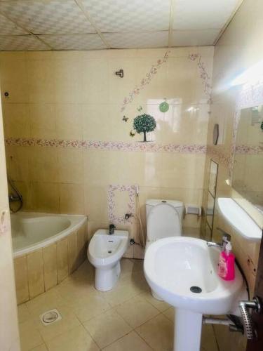 a bathroom with a toilet and a tub and a sink at Royal Suite: King Comfort in Ajman 