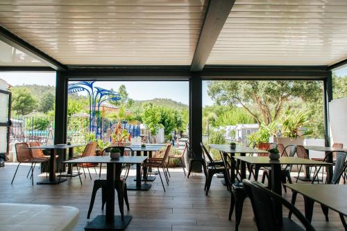 un restaurant vide avec des tables et des chaises ainsi qu'une aire de jeux dans l'établissement Camping Lou Cabasson, à Bormes-les-Mimosas