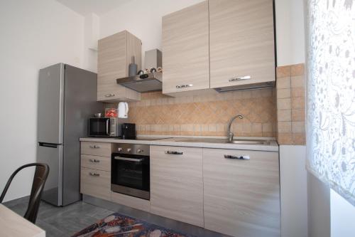a kitchen with wooden cabinets and a stainless steel refrigerator at Casa Vacanze Family House posizione centralissima in Civitavecchia