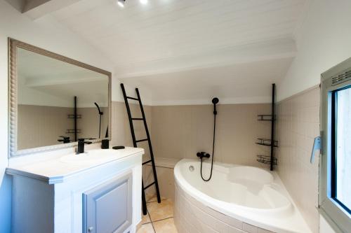 a bathroom with a tub and a sink and a mirror at Gîte Cerise - Maison climatisée avec piscine in Istres