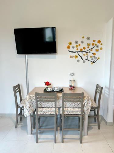 a dining room table with chairs and a tv on the wall at La Casetta tra Alghero e Stintino in Palmadula