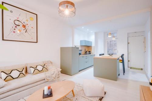 un salon avec un canapé et une cuisine dans l'établissement Le Verdé - Bel appt en plein cœur de Bordeaux, à Bordeaux