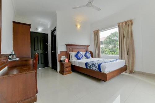 Schlafzimmer mit einem Bett, einem Schreibtisch und einem Fenster in der Unterkunft Centre Point in Kochi