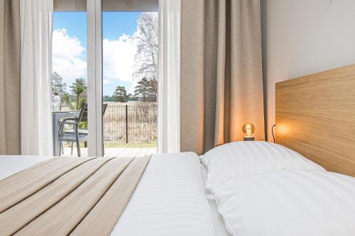 a bedroom with a bed and a large window at SMILGA & KOPA home - Mano jūra 2 Kunigiškiai - by Hello Sea homes in Palanga