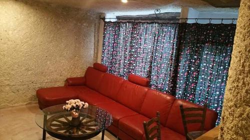 un soggiorno con divano rosso e finestra di Riolit Barlangszállás Szomolya a Szomolya