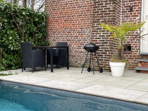 a grill and a table and chairs next to a brick wall at La Canopée des Arbres, Anna in Ellezelles
