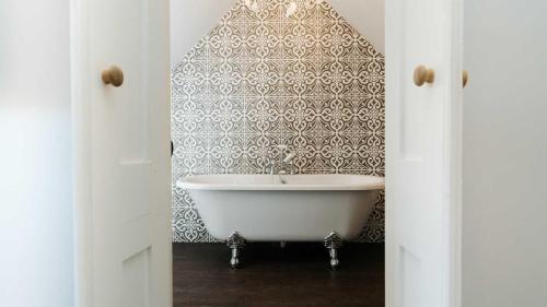 een wit bad in een badkamer met behang bij Dale House in Buxton