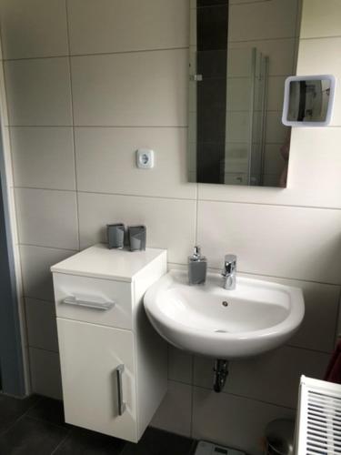 a white bathroom with a sink and a mirror at Muuske in Emden