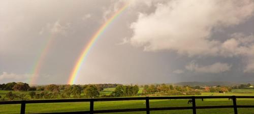 a rainbow in the sky over a field with a fence at Maison de charme en campagne, 5 min du haras du pin in Nonant-le-Pin
