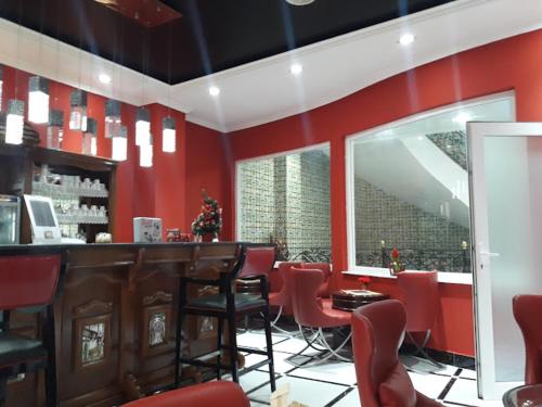 HOTEL SOLTANE في Husseïn Dey: مطعم بجدران حمراء وبار بكراسي حمراء